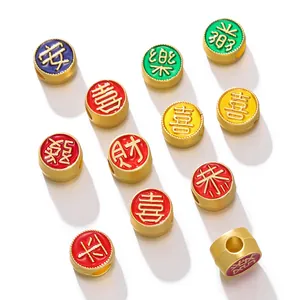 Vue détaillée de perles en or sablé coloré avec caractères chinois pour bijoux.