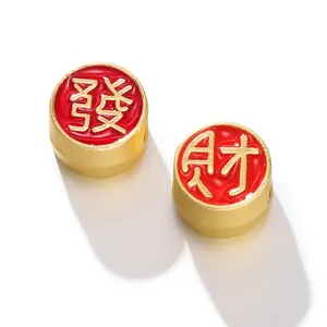 Vue macro de perles porte-bonheur en or sable avec émail rouge et signes chinois