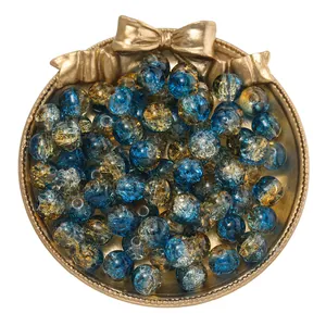 Detalle de cuentas de vidrio craquelado azul y dorado de 10 mm en una bandeja dorada