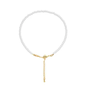 Detailed view of white pearl bead necklace with gold lobster clasp and extender chain