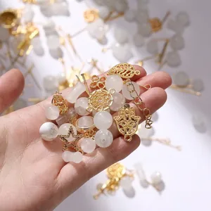 Close-up of mixed white faux jade beads and assorted golden metal charms for DIY