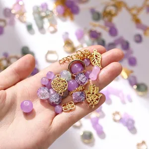 Detailed view of mixed purple glass beads and golden metal charms for DIY jewelry making