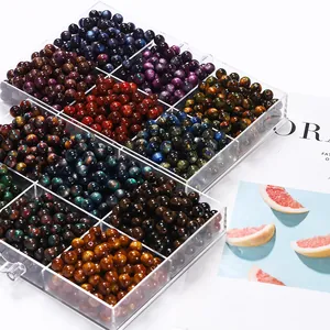 Macro view of assorted two-tone resin cat-eye beads in a transparent organizer box.