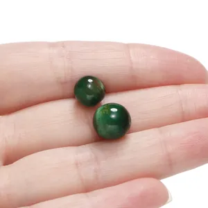 Close-up macro view of two green cat-eye resin beads held on a palm for DIY jewelry