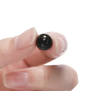 Detailed macro shot of a dark resin cat-eye bead held between fingers for DIY craft