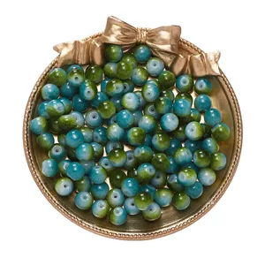 Macro view of green and blue gradient loose beads for DIY jewelry in a gold tray