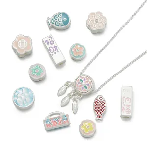 Close-up of matte silver Chinese style charms with enamel flower and fish motifs