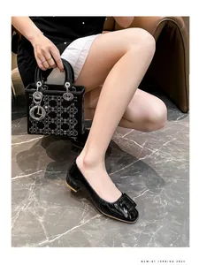 Close-up of black patent leather square-toe pumps with decorative buckle on a model
