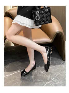 Detail view of black patent leather loafers with square buckle and block low heel