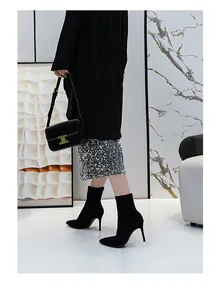 Detailansicht schwarzer Socken-Stiefeletten mit Stilettoabsatz und einem Paillettenrock.