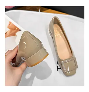 Close-up of beige patent leather square toe flats with chunky low heels and buckle.