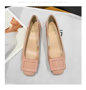 Close-up view of pink patent leather square-toe low-heel pumps with decorative buckle