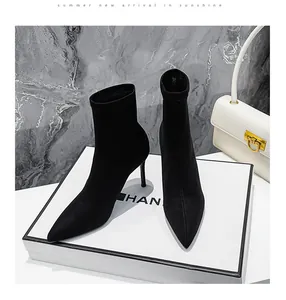 Elegante schwarze Stiletto-Socken-Stiefeletten mit spitzer Kappe auf einer weißen Box präsentiert