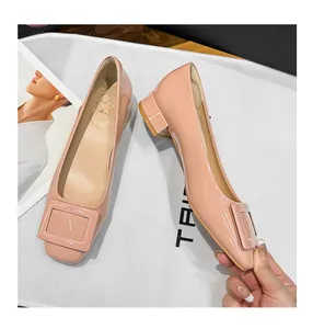 Close-up detail of elegant pink patent leather square toe pumps with a decorative buckle