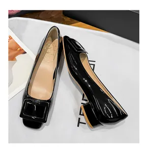 Elegant black patent leather pumps featuring a classic square buckle and low block heel
