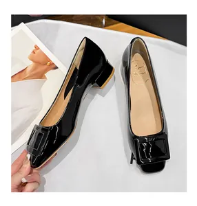 Close-up shot of black patent leather pumps featuring an elegant decorative square buckle