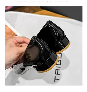 Close-up of black patent leather low heel pumps showing texture and block heel