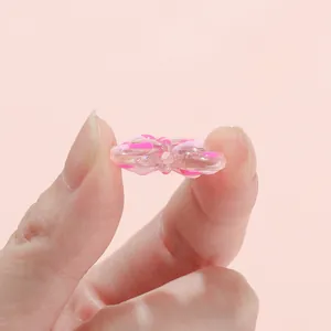 Gros plan d'une perle papillon en acrylique rose avec trou pour la création de bijoux DIY.