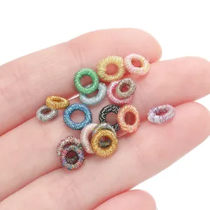 Detailed macro view of colorful metallic thread woven rings on fingers for DIY jewelry making