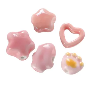 Detail view of pink ceramic beads with glossy cream texture in star and heart shapes