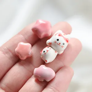 Close-up of pink star and white cat ceramic beads for DIY jewelry making.