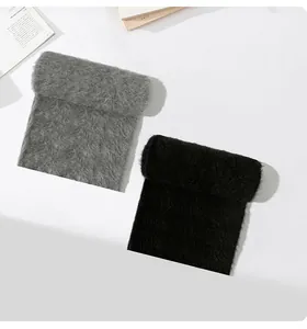 Dettaglio di due sciarpe di lana d'alpaca in grigio e nero su una superficie bianca pura