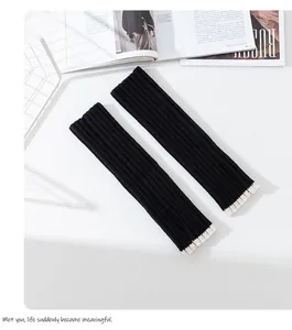 Detailansicht stilvoller schwarzer Strick-Armstulpen mit zarten weißen Rüschenkanten