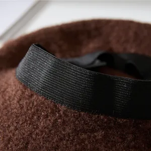 Close-up detail showing the soft brown plush fabric and black elastic band of the beret