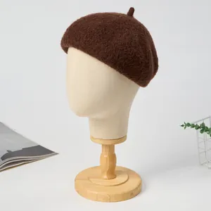 Detailed view of a thick and warm brown plush beret displayed on a wooden mannequin head