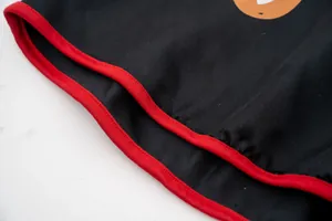 Dettaglio del mantello di Halloween per animali con bordo rosso su robusto tessuto nero.