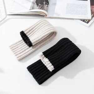 Kuschelige Strickstulpen aus Wolle in Schwarz und Beige mit weicher Rippenstruktur.