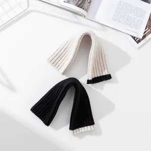 Warme Strickstulpen aus Wolle in Schwarz und Beige, fingerlos für den Winter-Look.