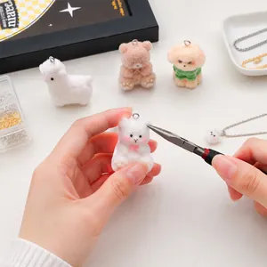 Primer plano del montaje de joyas DIY con colgante de oso flocado y alicates