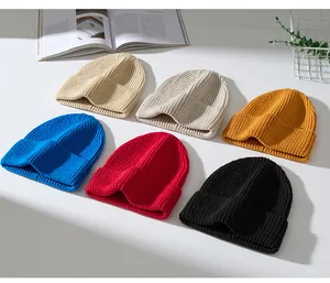 Verschiedene farbige grob gestrickte Beanie-Mützen auf einem minimalistischen weißen Tisch