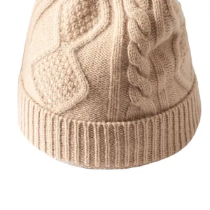 Primo piano di un berretto in maglia di lana beige con dettagli di trecce e rombi