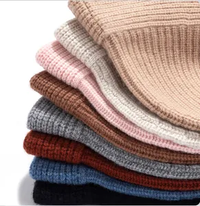 A stack of thick pure wool knitted beanies in multiple colors with soft ribbed texture