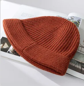 Close-up detail of a thick orange ribbed wool knit beanie on a magazine background