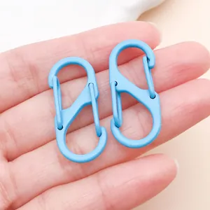 Vue détaillée de deux mousquetons en S bleu clair dans la main pour la création de bijoux