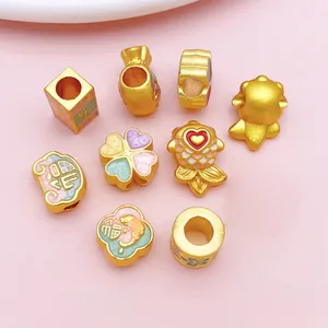 Collection of gold-toned alloy DIY charms including koi and clover shapes with enamel detail.