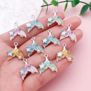 Vista detallada de dijes de cola de sirena de colores con estrellas y perlas en la mano