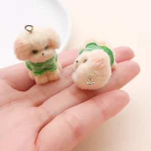 Detalle de dijes de perrito flocados que muestran textura suave y tamaño en la mano