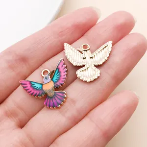 Gros plan détaillé de breloques colibri avec devant coloré et dos doré texturé.