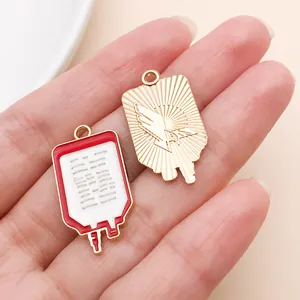 Detailansicht der rot-weißen Blutbeutel-Emaille-Anhänger für DIY-Schmuck in der Hand.