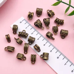 Detail view of antique bronze pendant bails with vintage patterns next to a white ruler.