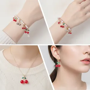 Detailed view of red rhinestone cherry jewelry set on models including necklace and earrings