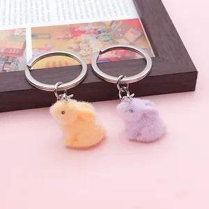 Vue détaillée des porte-clés lapin en peluche jaune et violet sur fond rose