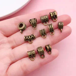 Close-up of various antique bronze bail beads with vintage patterns held in hand.
