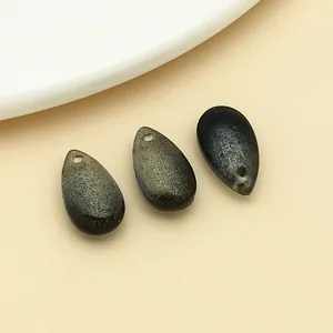 Detailed view of three shimmering gold-sprinkled glass teardrop pendants for DIY jewelry.