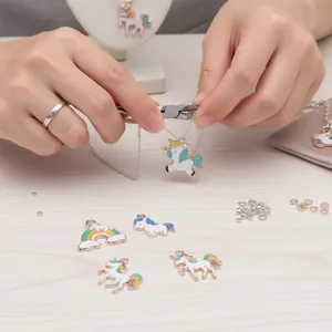 Close-up detail of hands assembling a necklace with colorful unicorn enamel charms