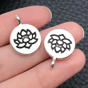 Gros plan de deux pendentifs ronds en argent antique avec des motifs de lotus de yoga gravés